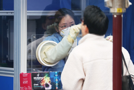 23일 오전 서울 서초구 고속버스터미널 앞에 마련된 임시선별검사소에서 의료진이 검체 채취를 하고 있다.  연합뉴스